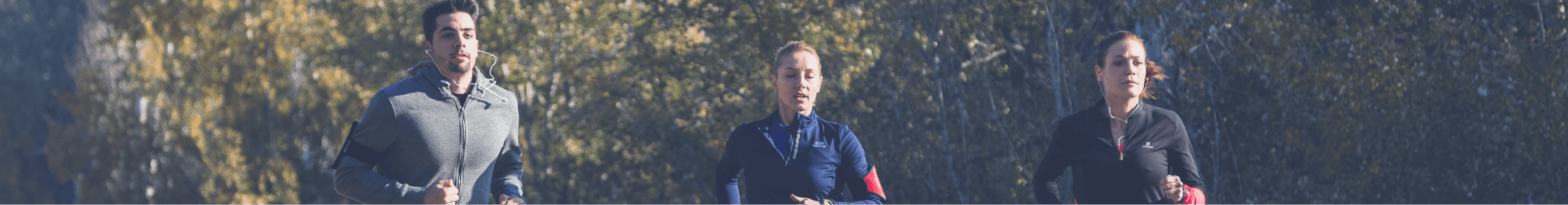 Drie mensen die buiten joggen, gekleed in sportkleding, in een bosrijk gebied tijdens de dag.